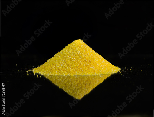 Heap of corn grits on black background with reflection photo