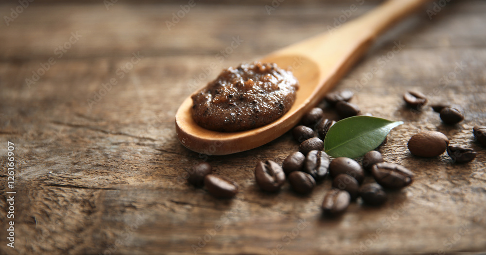Coffee body scrub in spoon on wooden background Coffee body scrub in spoon on wooden background
