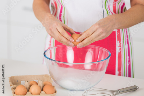 hands breaking an egg in bowl on table