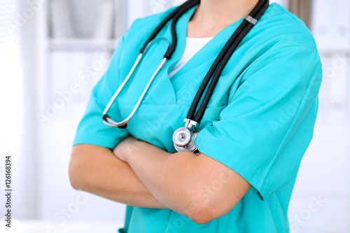 Female surgeon doctor is standing with arms crossed at hospital. Physician is ready to examine patient
