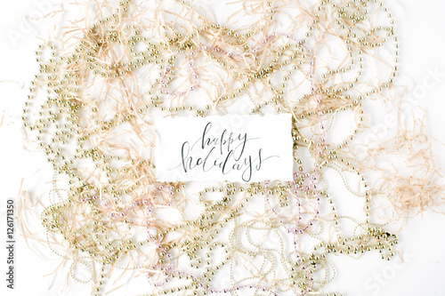 calligraphy words happy holidays and christmas tinsel decoration. flat lay, top view