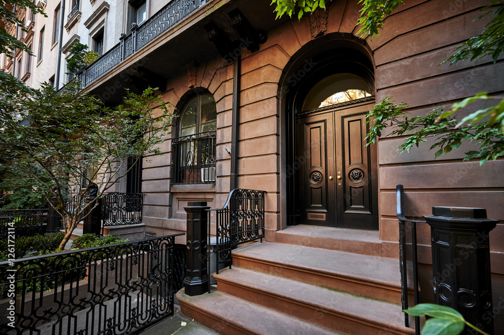 the front steps and door of an ornate brownstone building