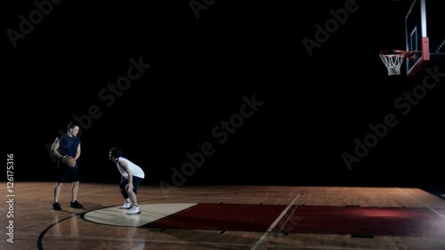 A basketball player runs down the court past defenders and then scores
