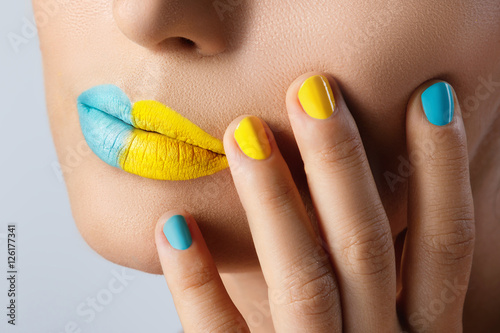 Female lips with two different lipsticks and colorful nails photo