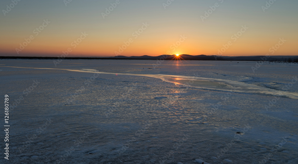 Beautiful sunset on a frozen lake. Winter came frozen lake.