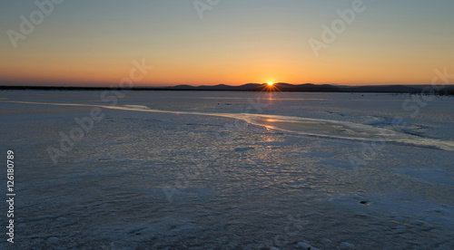 Beautiful sunset on a frozen lake. Winter came frozen lake.