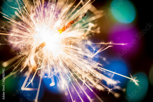 Christmas sparkler on colorful lights background