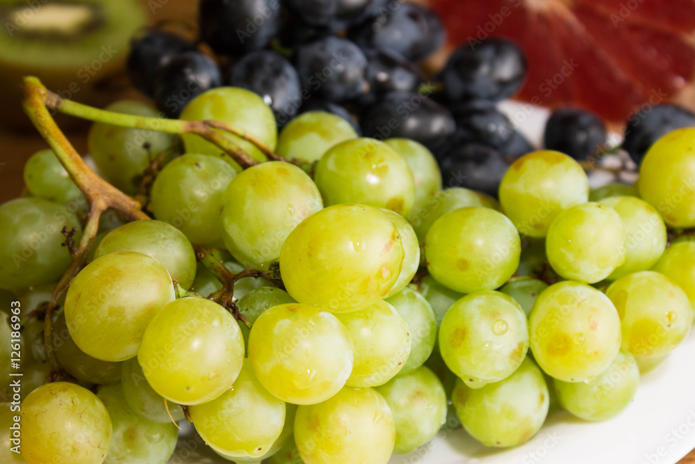 Green and black grapes in a white plate