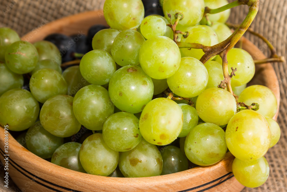 Green and black grapes in a wooden plate Green and black grapes in a wooden plate