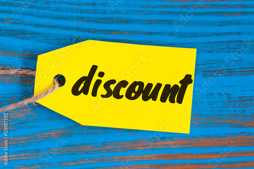 Discount tag label yellow color on blue wooden background