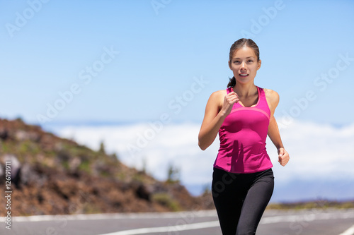 Fit sport athlete running woman runner jogging outdoor on road training for marathon race run. Asian young woman running outdoors working out cardio. Beautiful fit fitness model in her 20s.