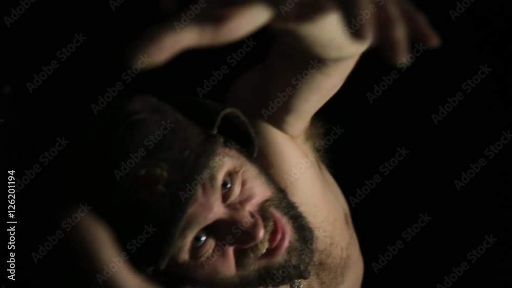scary evil sinister bearded man with smirk, reaching for the camera. strange Russian man with a naked torso and a woolen hat scary evil sinister bearded man with smirk, reaching for the camera. strange Russian man with a naked torso and a woolen hat