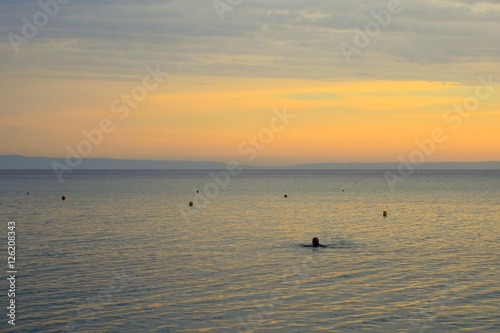 Man swimming in Aegean sea at sunrise
