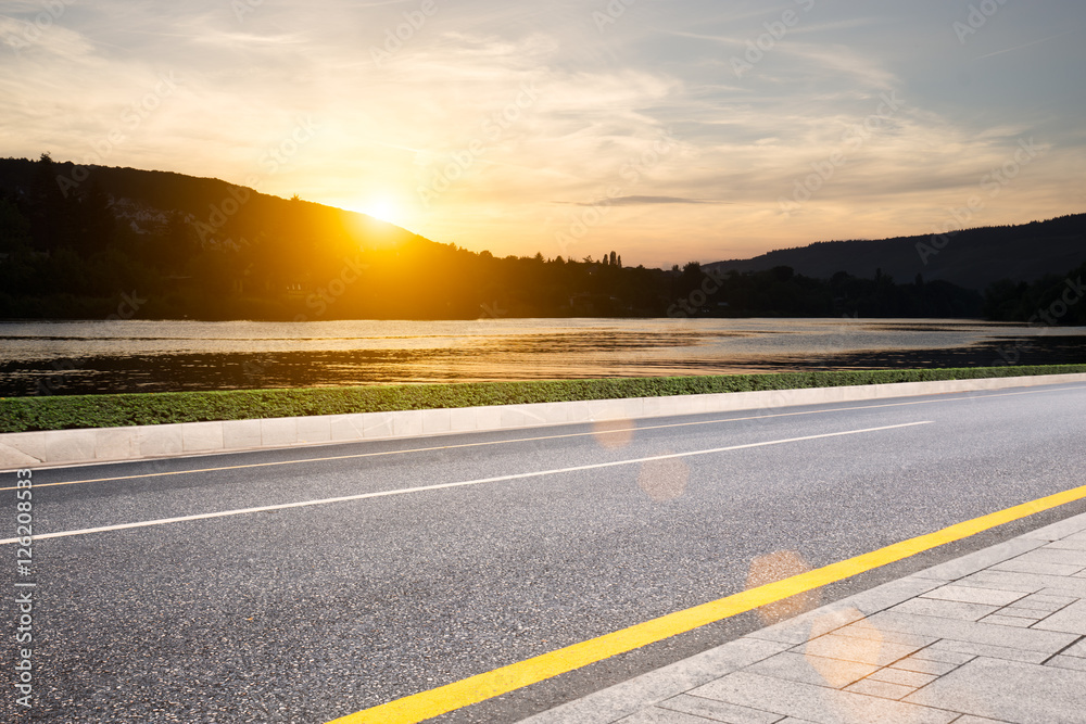 Fototapeta premium sunrise from hill on view from empty rural road
