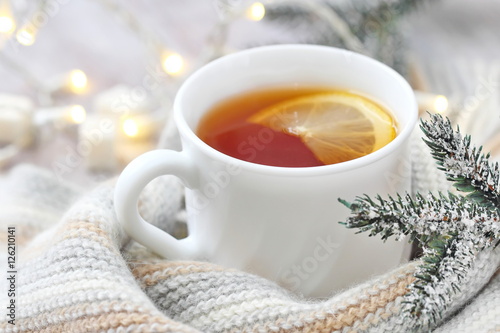 Cup of hot tea with lemon and woolen scarf