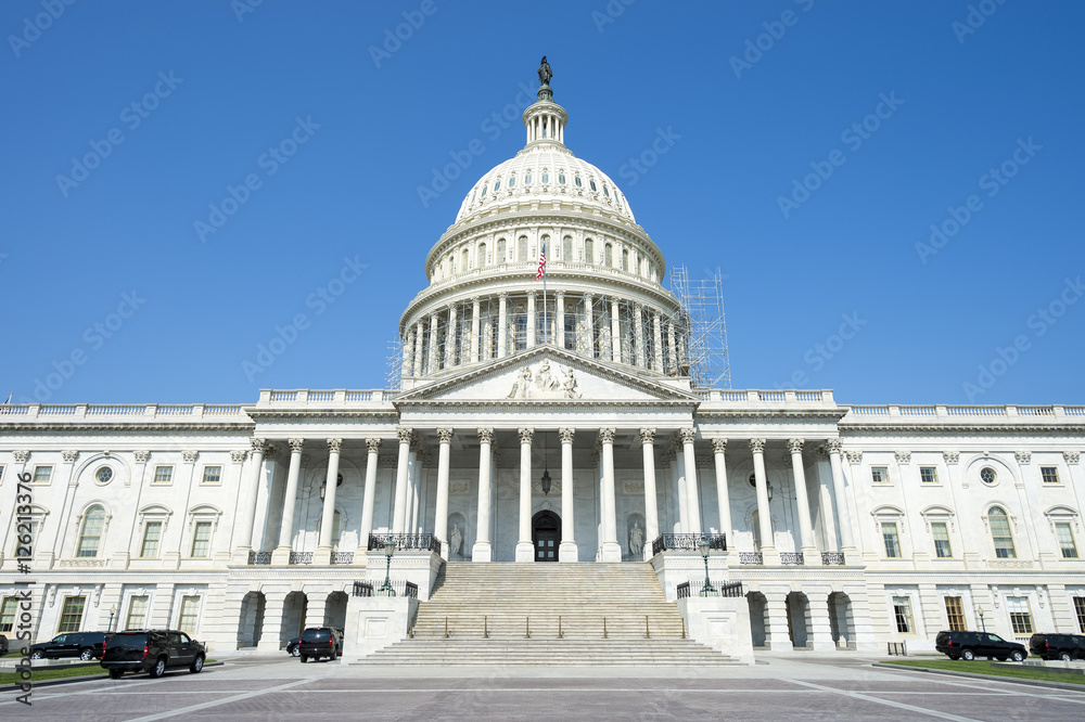 Front view of the Capitol Building in Washington DC, USA from in front of the entrance staircase under bright blue sky Front view of the Capitol Building in Washington DC, USA from in front of the entrance staircase under bright blue sky