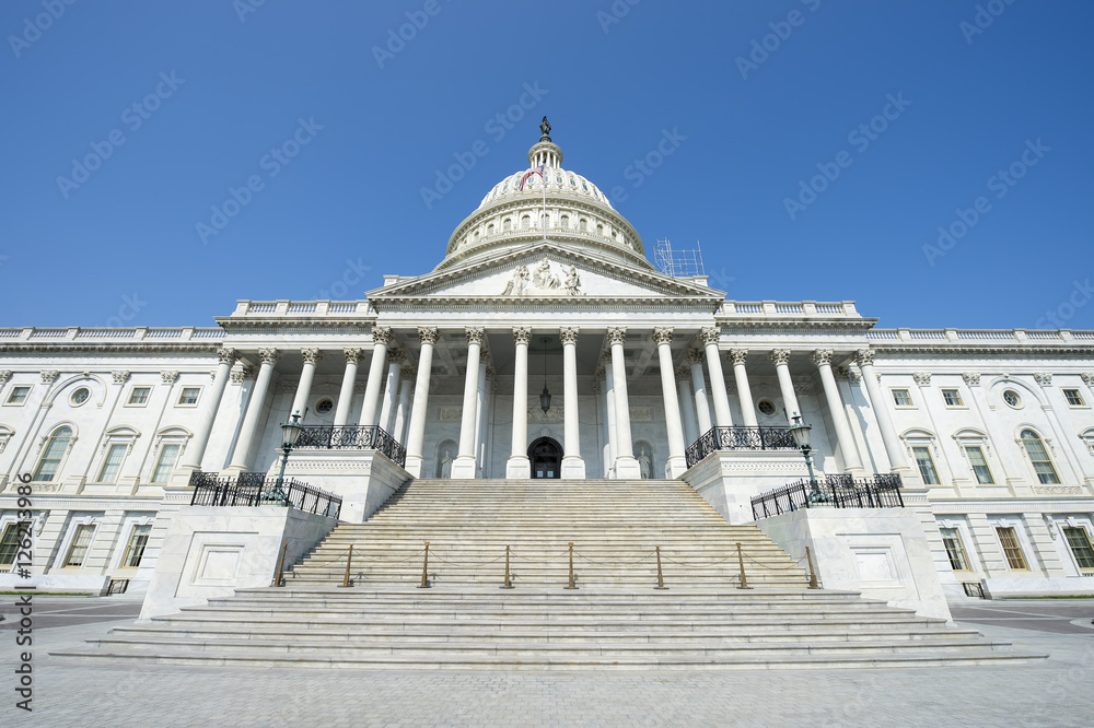 Front view of the Capitol Building in Washington DC, USA from in front of the entrance staircase under bright blue sky