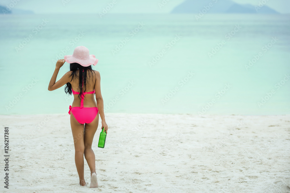 Young woman walking with beer bottle on beach,remote tropical beaches and countries. travel concept Young woman walking with beer bottle on beach,remote tropical beaches and countries. travel concept