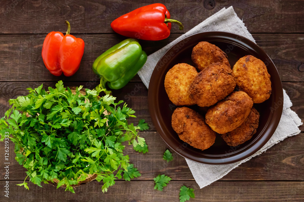 Meat mini-rolls (cutlet) with boiled egg in a clay bowl on dark wooden background. The top view
