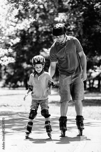 Father and son roller skating. Boy learning roller skating in park
