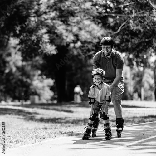 Family roller skating. Father roller skating in park with son
