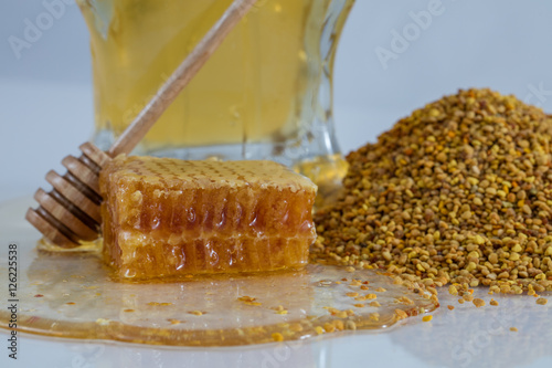 Honeycomb on a table with honey in a jar a wooden dipper and bee pollen granules 1