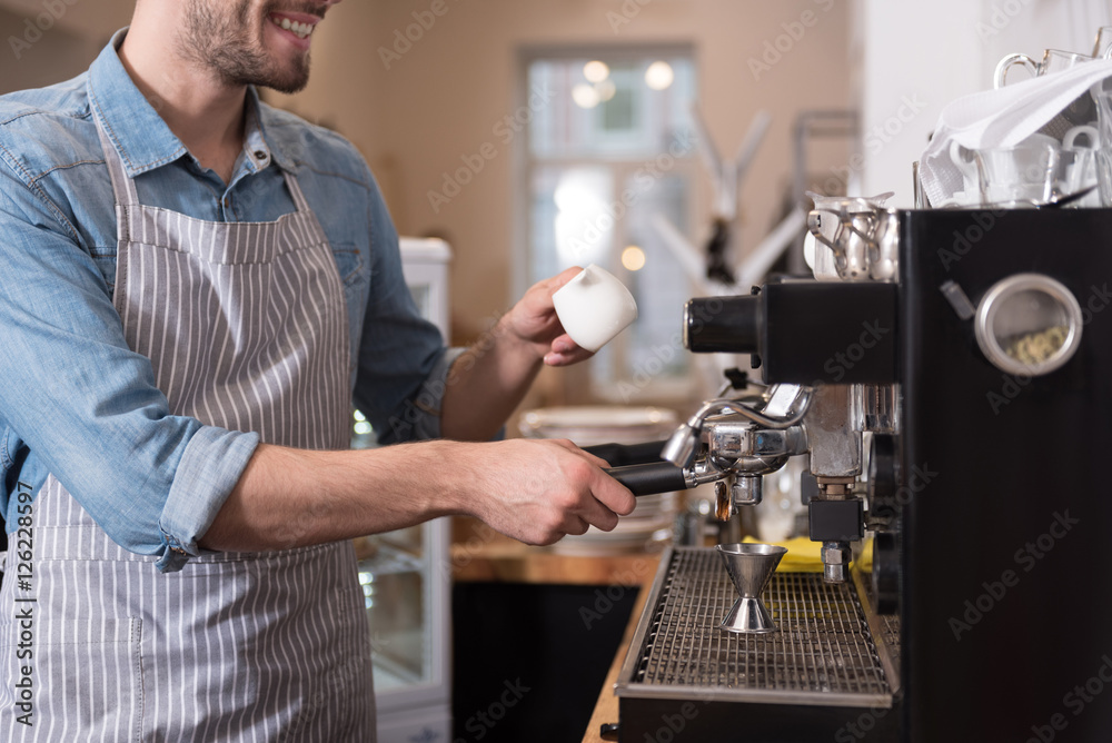 Pleasant smiling man using coffee machine.