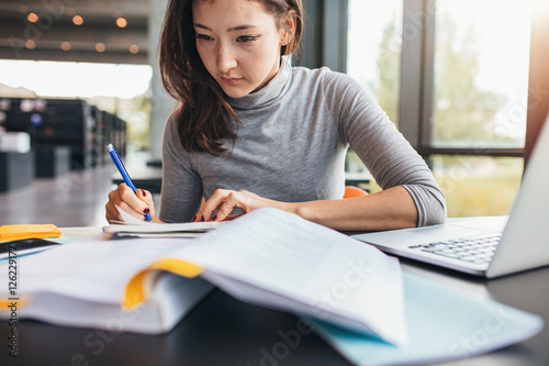 Student taking notes from textbook photo