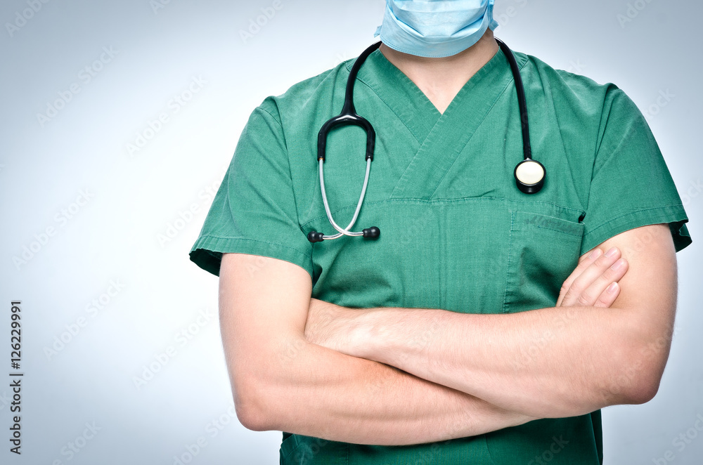 The doctor in green scrubs folded his arms across his chest. Around his neck hangs a black doctor pediatric stethoscope. The doctor in green scrubs folded his arms across his chest. Around his neck hangs a black doctor pediatric stethoscope.