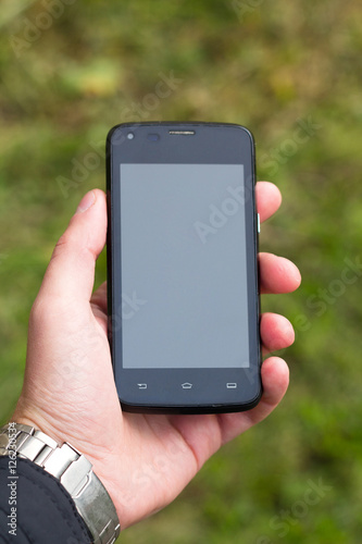 Image of a man holding smartphone in his hand with a watch on hi