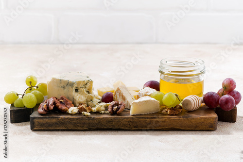 cheeseboard, grapes and honey on a white background