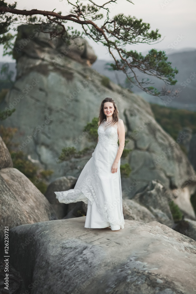 Gorgeous bride in elegant dress holding bouquet posing near forest Gorgeous bride in elegant dress holding bouquet posing near forest