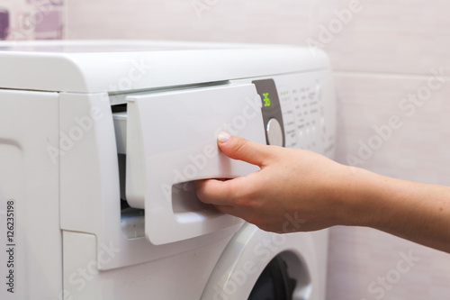 Woman pours the liquid powder in washing machine