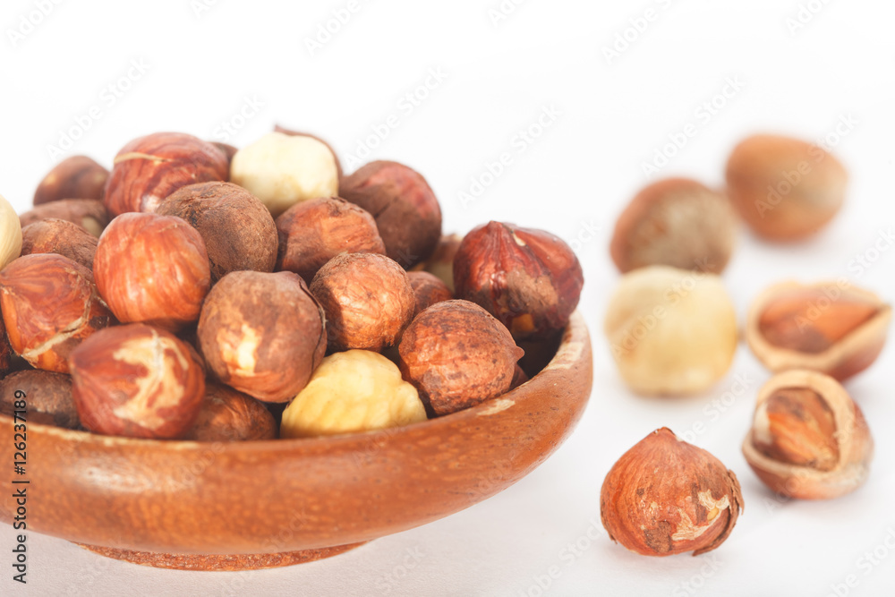 Hazelnuts in a wooden bowl isolated on white background. Hazelnuts in a wooden bowl isolated on white background.