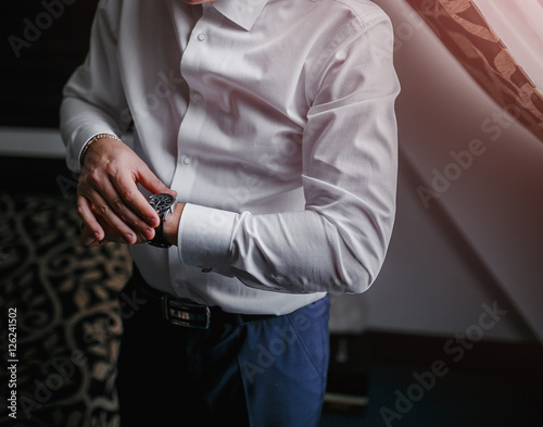 The man in the white shirt near window wears watches. © EdNurg