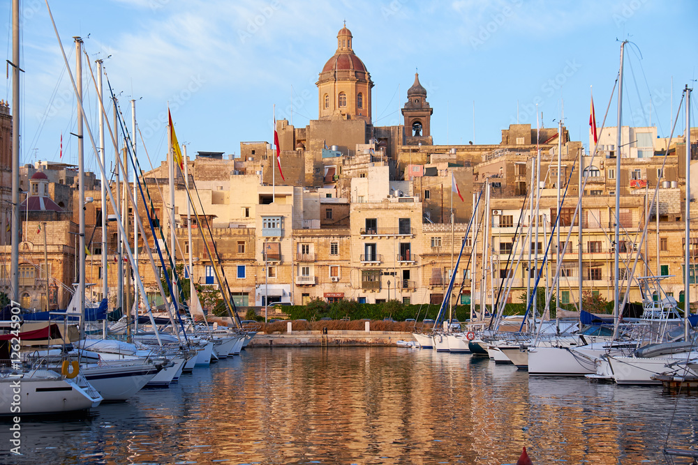 The view of Birgu (old capital Vittoriosa) with Our Lady of Annunciation Church (St. Dominic's Church) big dome over the Dockyard bay with moored yacht. Malta
