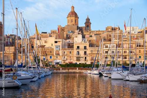 The view of Birgu (old capital Vittoriosa) with Our Lady of Annunciation Church (St. Dominic's Church) big dome over the Dockyard bay with moored yacht. Malta