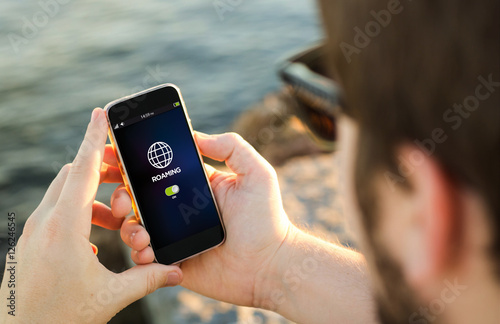 Quadro su tela Man using his mobile phone on the coast roaming
