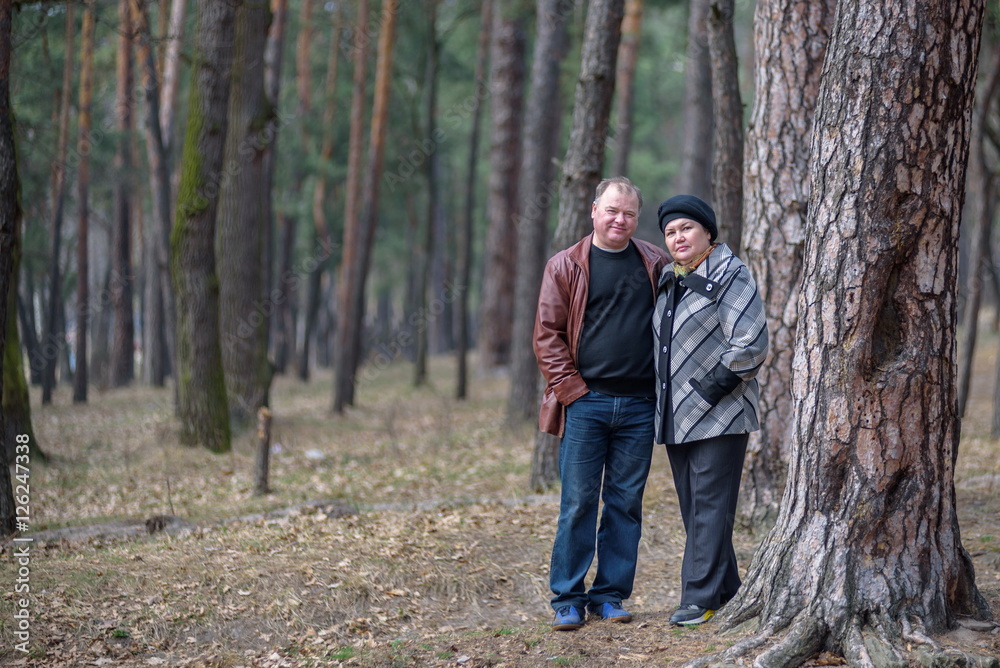 Old couple walking in the forest. Having a good time together. Smiling and talking on autumn or spring