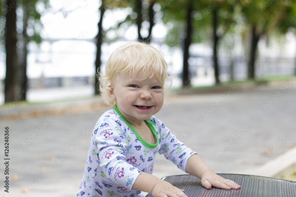 A small child learns to walk near the benches, toddler A small child learns to walk near the benches, toddler