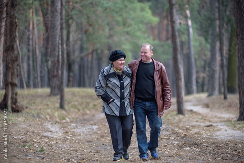 Old couple walking in the forest. Having a good time together. Smiling and talking on autumn or spring © pahis