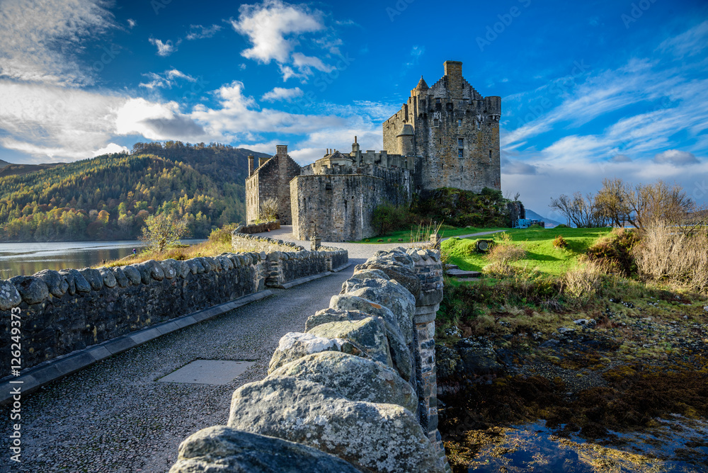 Fototapeta premium Majestic Eilean Donan castle on beautiful autumn day - with sunny foreground, dramatic sky and amazing scenery