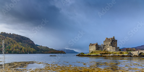 Majestic Eilean Donan castle on beautiful autumn day - with sunny foreground  dramatic sky and amazing scenery