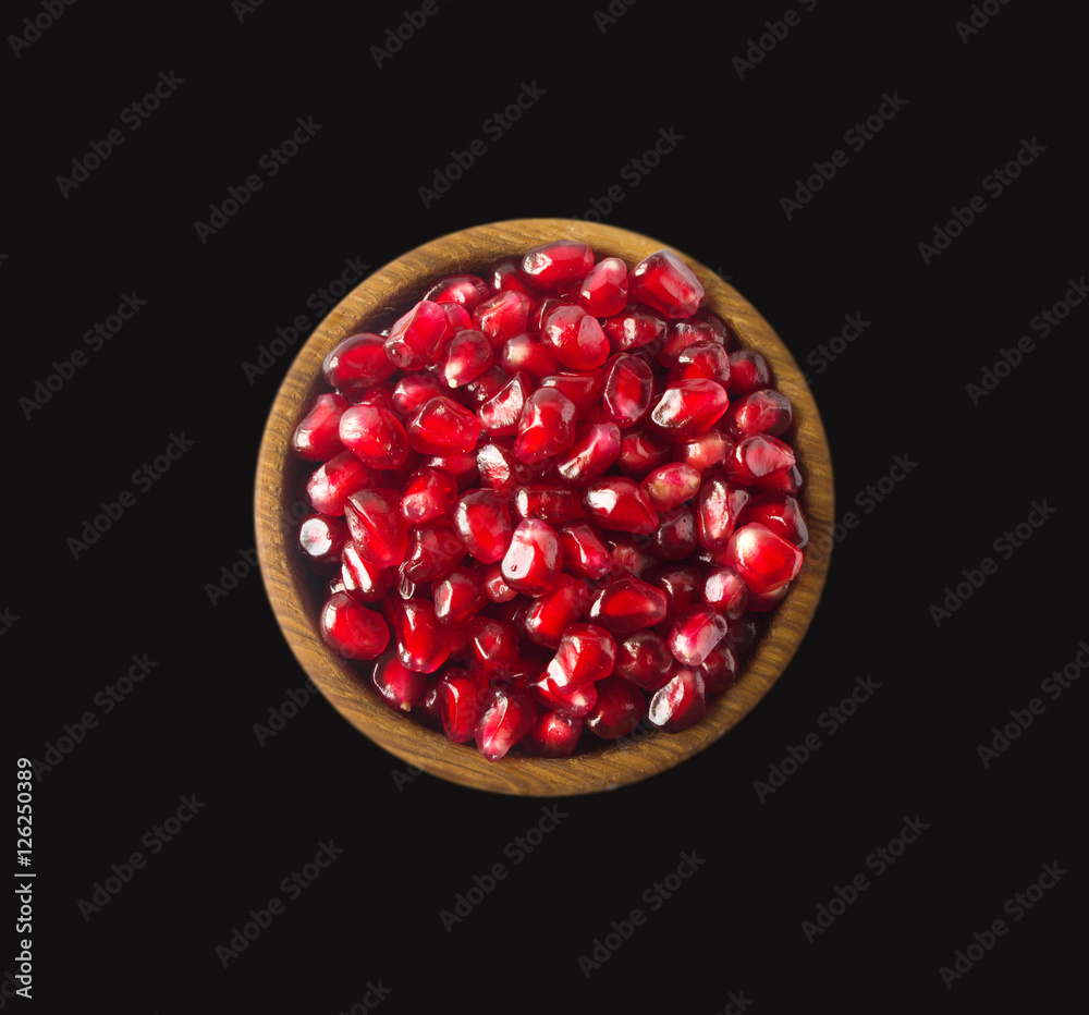 Red pomegranate seeds. Grains of a pomegranate in woooden bowl isolated on black background. Top view. Red pomegranate seeds. Grains of a pomegranate in woooden bowl isolated on black background. Top view.