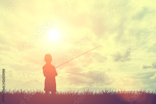 Silhouette grass and little boy fishing with sky and clouds during sunset, Concept of light and shadow
