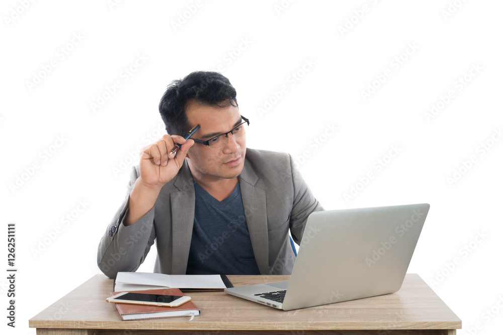 businessman holding a pen thinking sitting at his desk behind hi businessman holding a pen thinking sitting at his desk behind hi