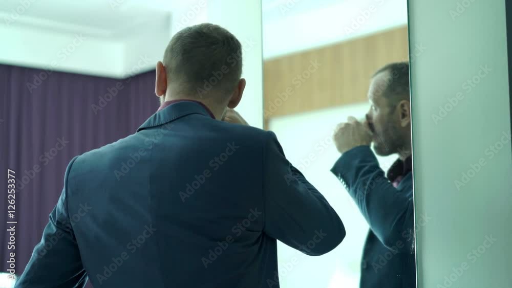 Young businessman preparing, checking his look in the mirror, and drinking tea 4K
Young businessman preparing, checking his look in the mirror, and drinking tea 4K