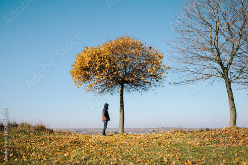 man standing under autumn tree.