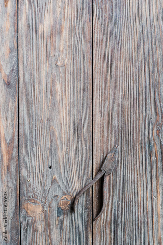 Old rusty steel pliers on wooden background