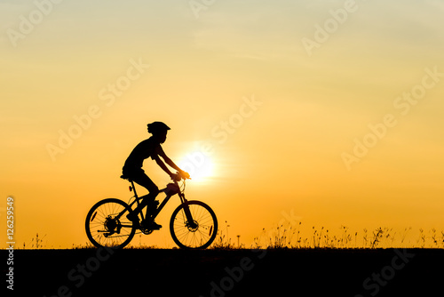 Silhouette of cyclist motion on sunset background